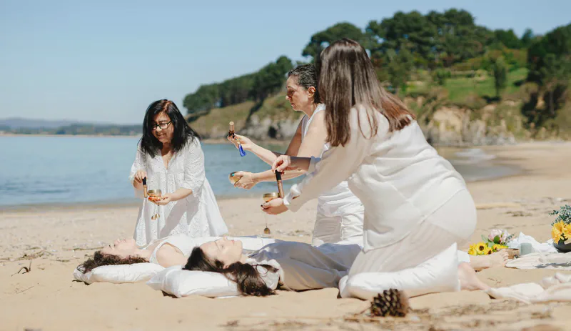 Un grupo realizando una ceremonia de sanación con sonido en la playa
