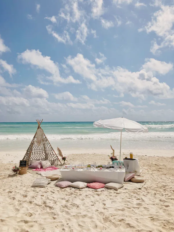 Minimalist beach picnic with white table and pink cushions
