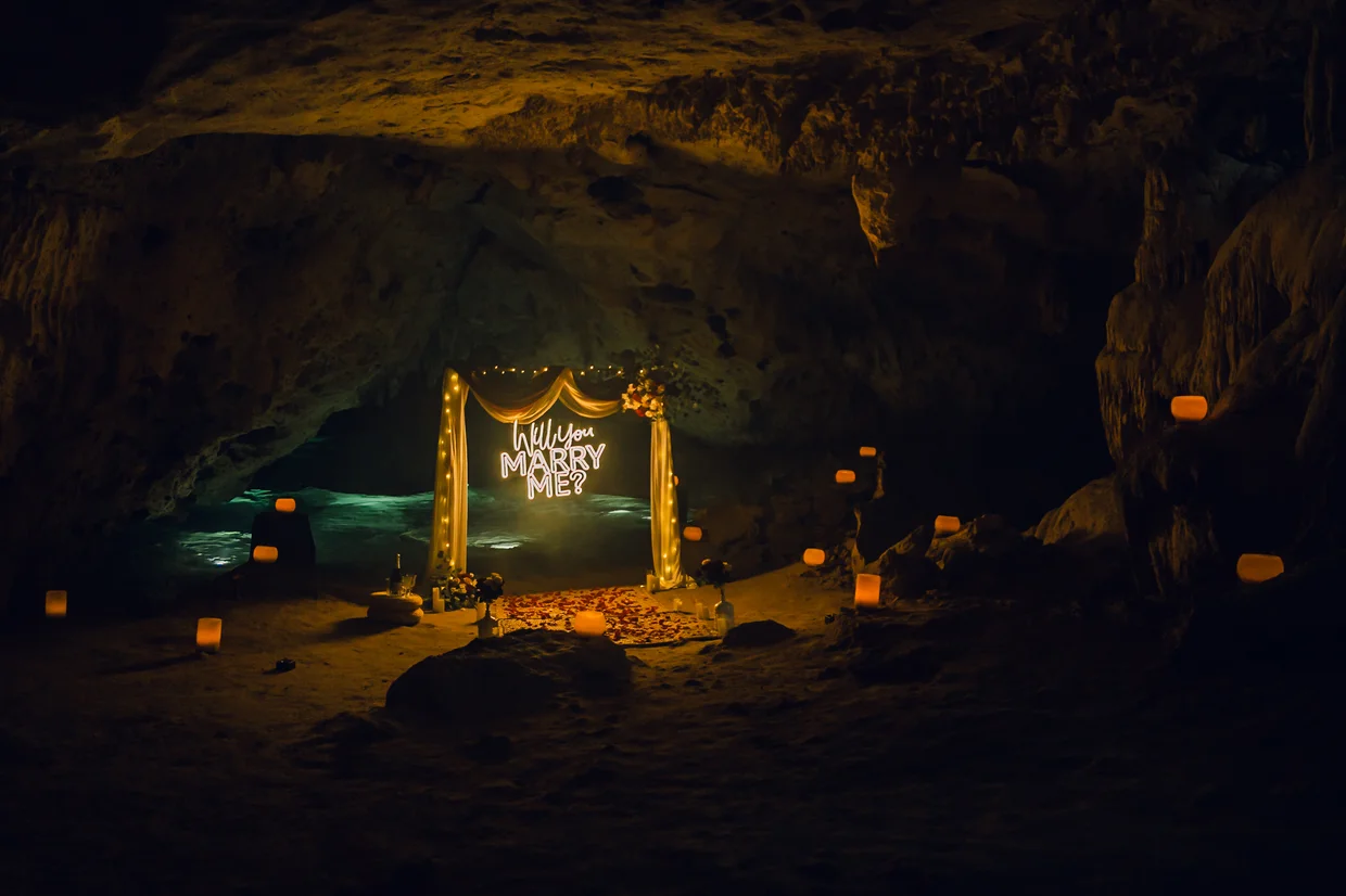 Romantic cave proposal scene with illuminated ‘marry me’ sign