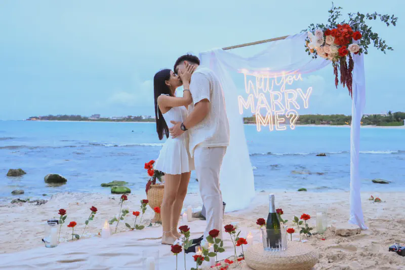 Romantic beach proposal setup with teepee and flowers