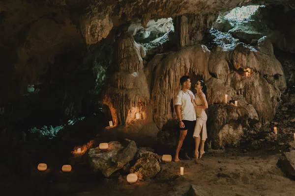 Pareja abrazándose en una cueva de cenote, iluminada por la luz de las velas y formaciones rocosas naturales