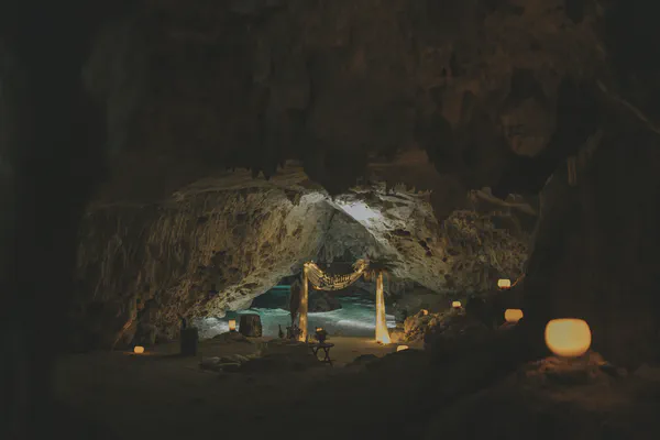 Toma amplia de una cueva de cenote decorada para una cena romántica con velas brillantes y un fondo de piscina tranquila