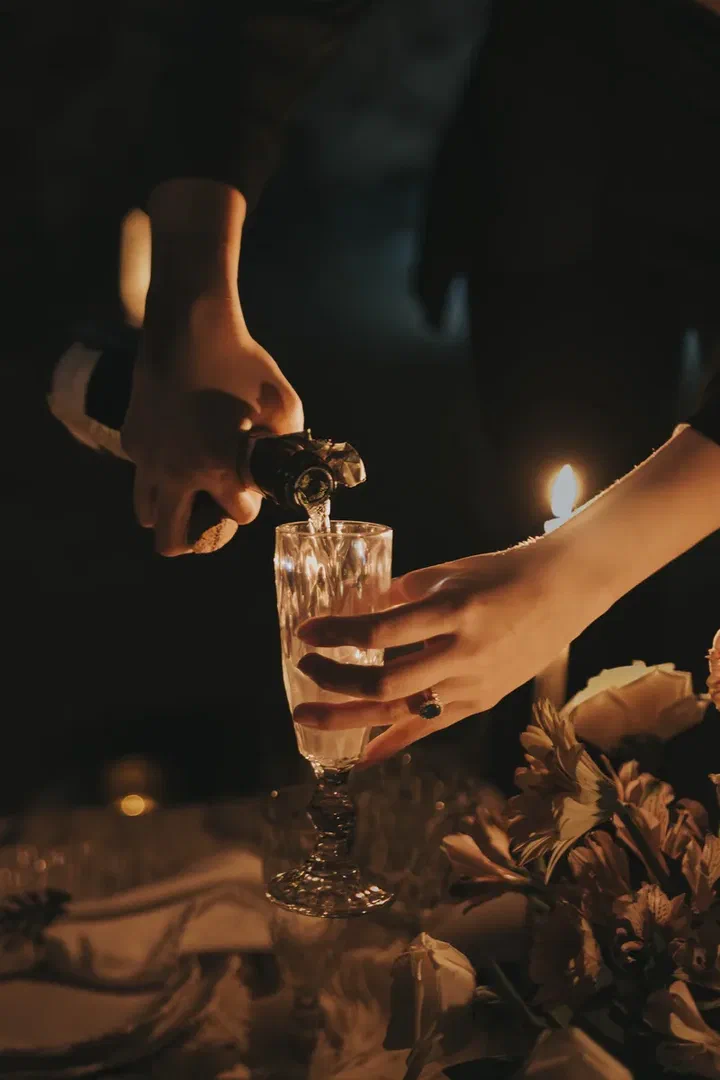 Champagne poured into a crystal flute by candlelight.