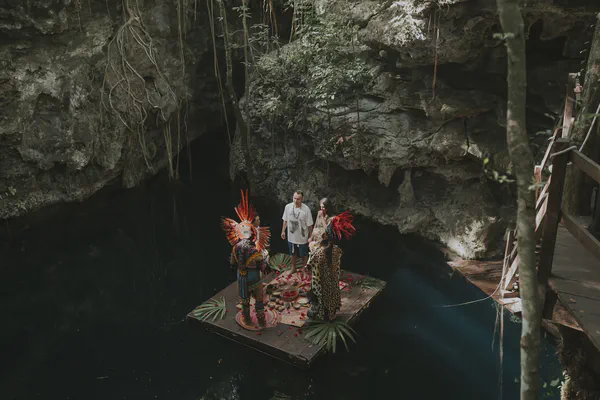 Wide view of a sacred cenote ceremony platform surrounded by ancient limestone walls and crystal waters