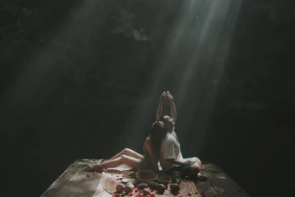 Romantic cenote cave wedding ceremony in Mexican Caribbean with dramatic natural light beams illuminating couple during spiritual vow renewal ritual