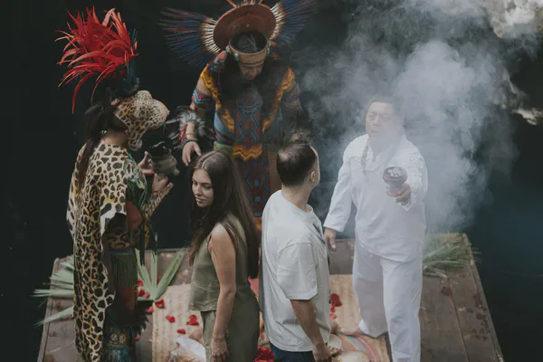 Traditional Mayan ceremony blessing in a sacred cenote cave with ceremonial elements and natural light