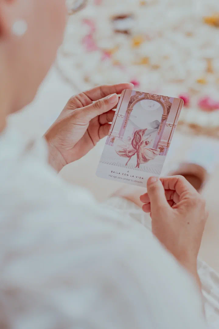 Hands hold an illustrated intention card above a bed of flower petals.
