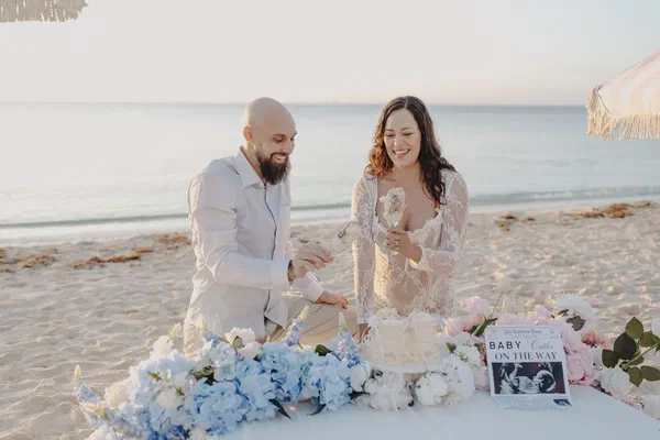 Couple cutting their reveal cake among pastel flowers on a Playa del Carmen beach