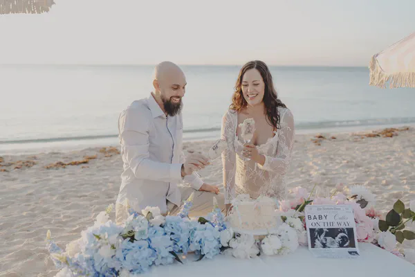 Couple cutting their reveal cake among pastel flowers on a Playa del Carmen beach