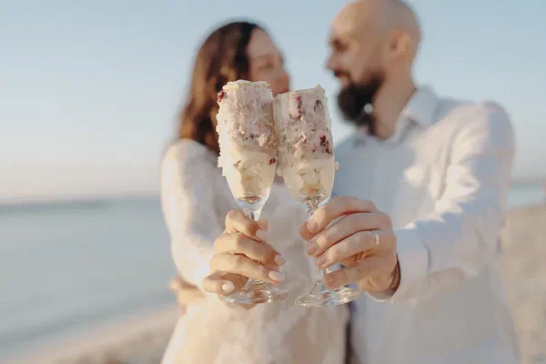 Couple toasting with slices of reveal cake after their beach gender reveal