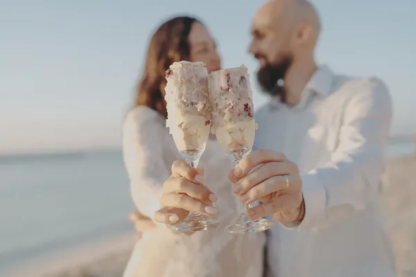 Couple toasting with slices of reveal cake after their beach gender reveal