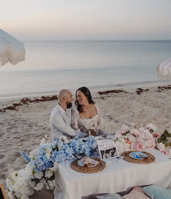Expectant couple seated at their decorated picnic table on the beach in Riviera Maya
