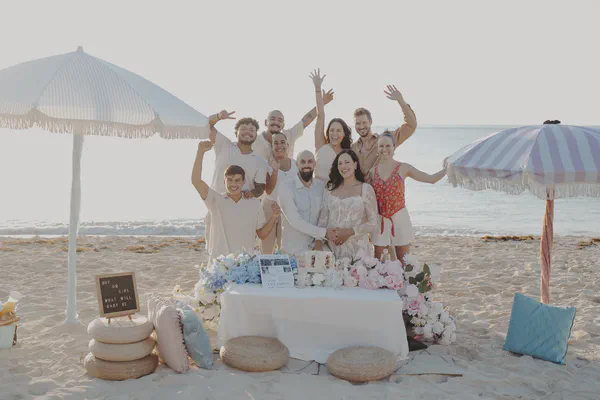 Parents-to-be smiling with family during a beach celebration in Playa del Carmen