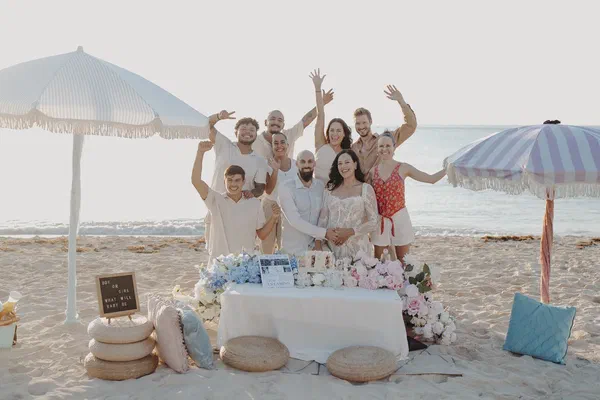 Parents-to-be smiling with family during a beach celebration in Playa del Carmen