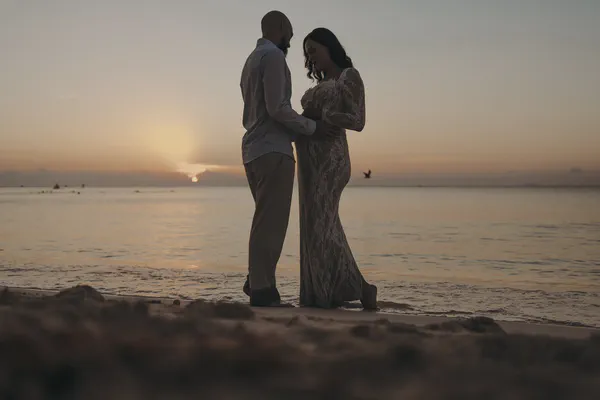 Couple embracing at sunrise during their beach gender reveal in Playa del Carmen