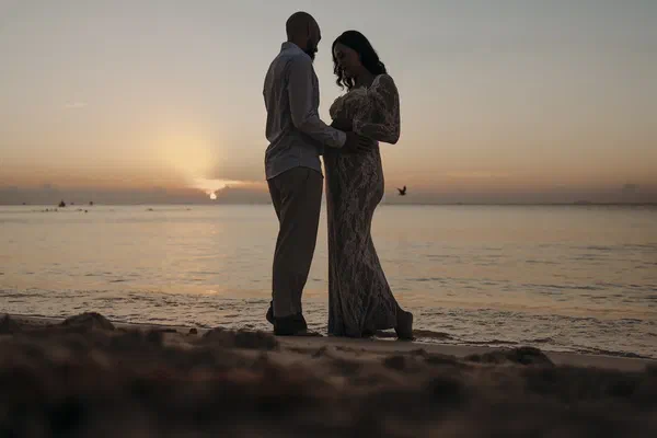 Couple embracing at sunrise during their beach gender reveal in Playa del Carmen