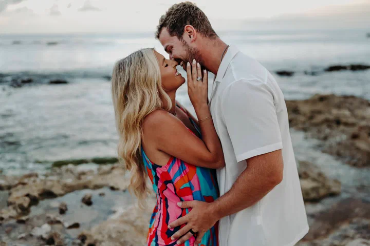 Couple embracing beside the sea, with the woman in a colorful dress