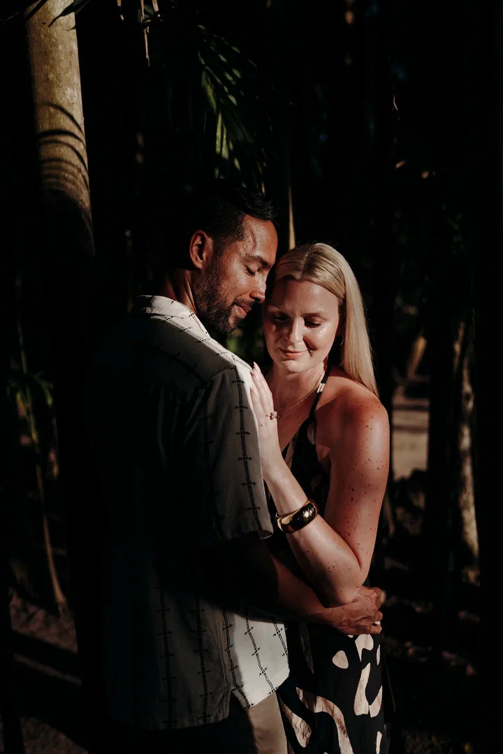Couple embracing in soft light in a shaded tropical garden