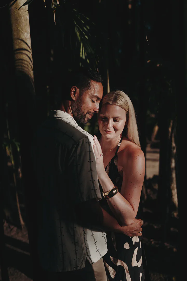 Couple embracing in soft light in a shaded tropical garden