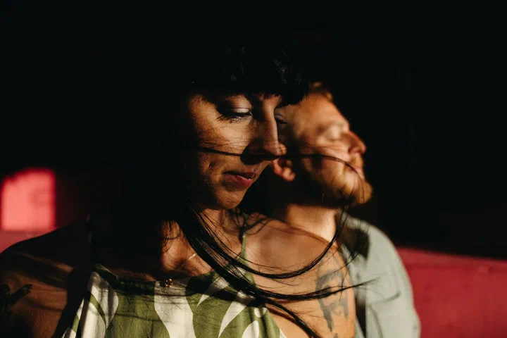 Close-up of a couple with closed eyes and windswept hair in warm light