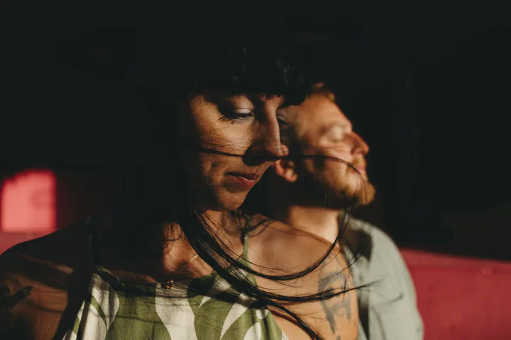 Close-up of a couple with closed eyes and windswept hair in warm light