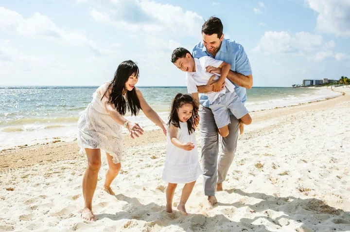 Parents playing with their children beside the turquoise sea