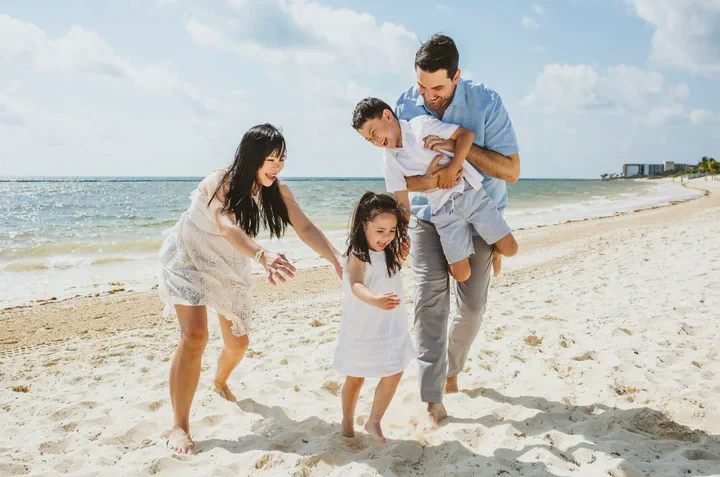 Parents playing with their children beside the turquoise sea